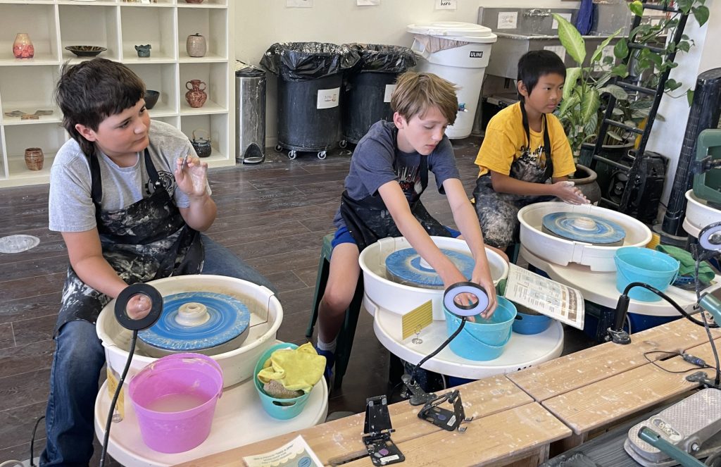 Students learn to use pottery wheels in a ceramics class.