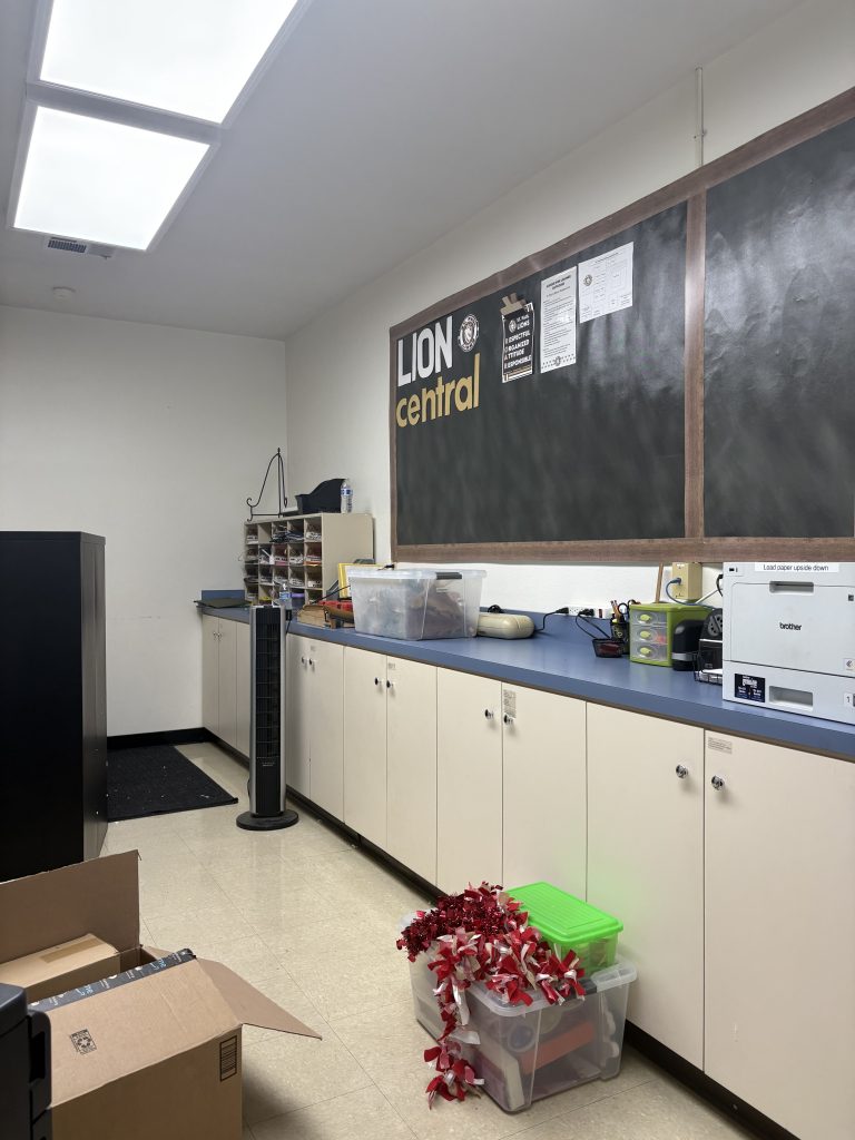 Our copy room features the lion central announcement board, blue counter and cream-colored cabinets along one wall. This image is prior to our office makeover.