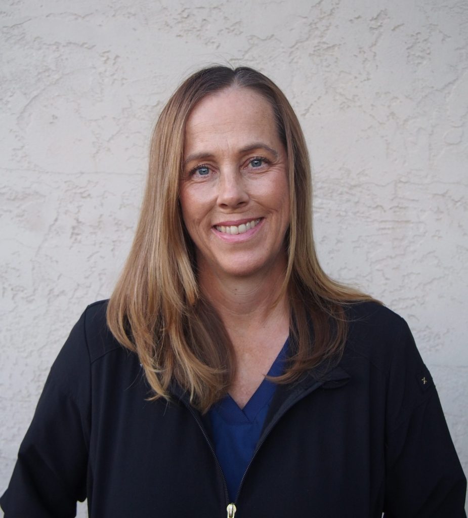 Nicole Cook is the St Paul Mission and Ministry Board secretary. This headshot shows her in front of a textured wall, looking every bit as friendly as you'd expect your local vet to be. She has medium-length highlighted brunette hair, a friendly smile and wears a sensible black sweater over a navy blouse.