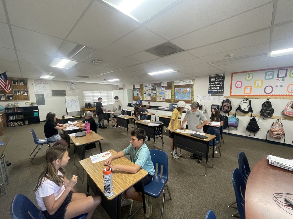 Sixth-grade students sit across from each other in Mr. Stallings class at St. Paul School in Merced to play fractions board games they created during their math period.